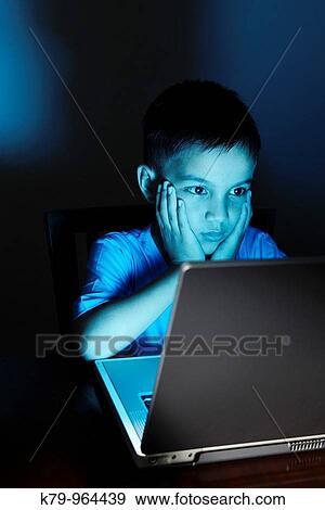 Stock Photo - Young Asian boy using laptop at night.. Fotosearch