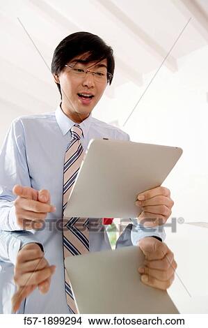 Young Asian businessman communicating on his Tablet computer View Large Photo Image Picture - Young Asian businessman communicating on his Tablet computer. Fotosearch