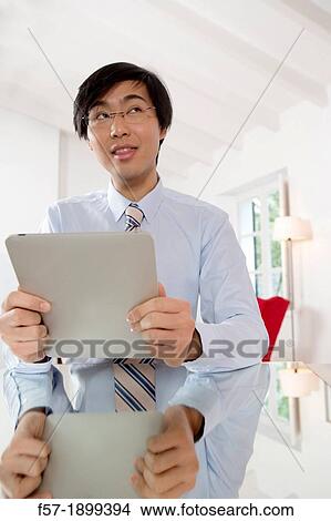 Young Asian businessman communicating on his Tablet computer View Large Photo Image Picture - Young Asian businessman communicating on his Tablet computer. Fotosearch