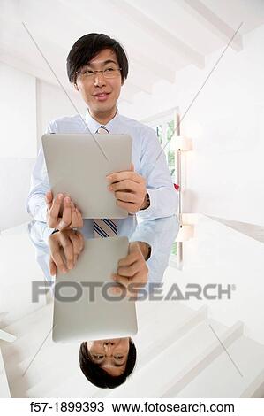 Young Asian businessman communicating on his Tablet computer View Large Photo Image Stock Image - Young Asian businessman communicating on his Tablet computer. Fotosearch
