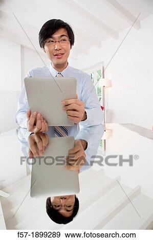 Young Asian businessman communicating on his Tablet computer View Large Photo Image Stock Photo - Young Asian businessman communicating on his Tablet computer. Fotosearch