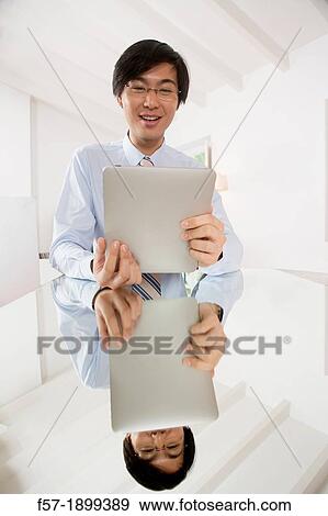 Stock Photo - Young Asian businessman communicating on his Tablet computer. Fotosearch