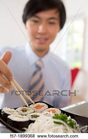 Young Asian businessman eating sushi View Large Photo Image Stock Photo - Young Asian businessman eating sushi. Fotosearch