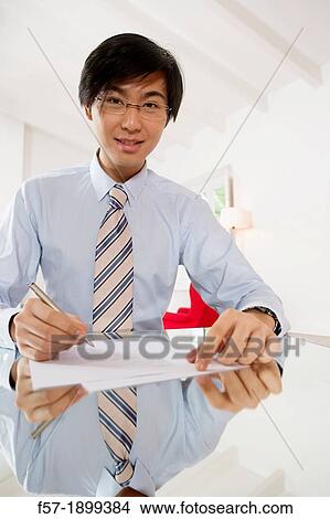 Picture - Young Asian businessman signing contracts. Fotosearch