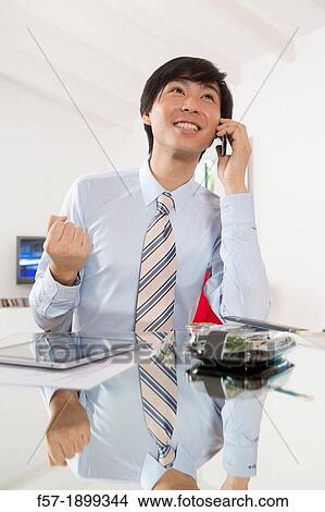 Young Asian businessman talking on his smartphone View Large Photo Image Picture - Young Asian businessman talking on his smartphone. Fotosearch