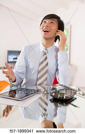 Young Asian businessman talking on his smartphone View Large Photo Image Stock Image - Young Asian businessman talking on his smartphone. Fotosearch