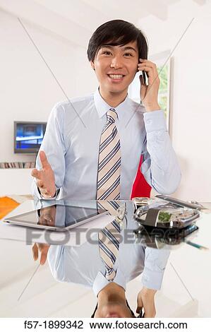 Young Asian businessman talking on his smartphone View Large Photo Image Stock Image - Young Asian businessman talking on his smartphone. Fotosearch