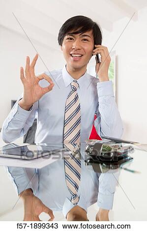 Young Asian businessman talking on his smartphone View Large Photo Image Stock Image - Young Asian businessman talking on his smartphone. Fotosearch