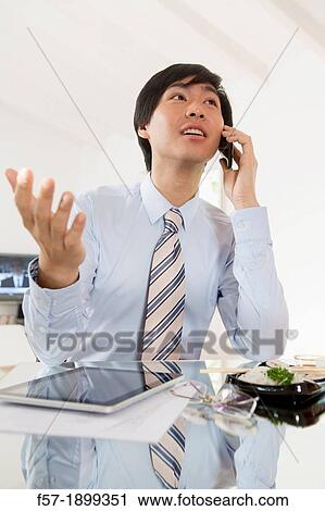 Young Asian businessman talking on his smartphone View Large Photo Image Stock Image - Young Asian businessman talking on his smartphone. Fotosearch
