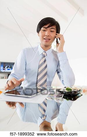 Young Asian businessman talking on his smartphone View Large Photo Image Stock Image - Young Asian businessman talking on his smartphone. Fotosearch