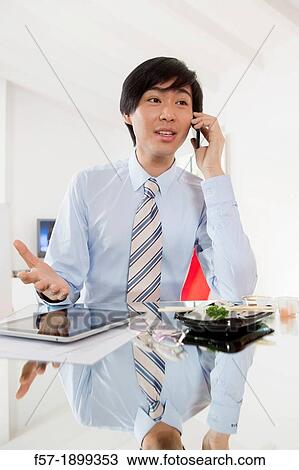 Young Asian businessman talking on his smartphone View Large Photo Image Stock Image - Young Asian businessman talking on his smartphone. Fotosearch