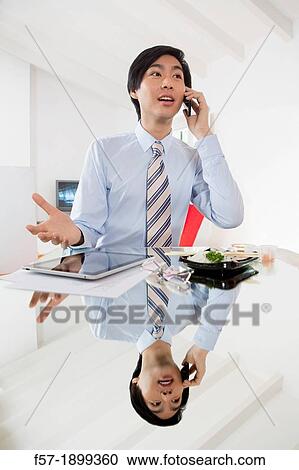 Young Asian businessman talking on his smartphone View Large Photo Image Stock Image - Young Asian businessman talking on his smartphone. Fotosearch