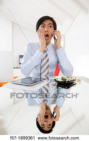 Stock Image - Young Asian businessman talking on his smartphone. Fotosearch