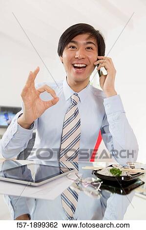 Young Asian businessman talking on his smartphone View Large Photo Image Stock Image - Young Asian businessman talking on his smartphone. Fotosearch
