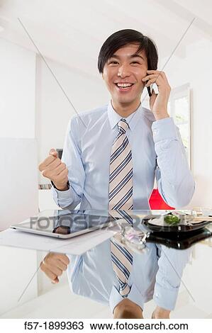Young Asian businessman talking on his smartphone View Large Photo Image Stock Image - Young Asian businessman talking on his smartphone. Fotosearch