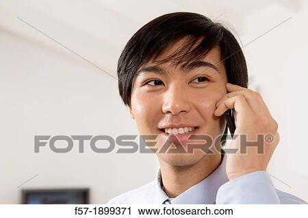 Young Asian businessman talking on his smartphone View Large Photo Image Stock Image - Young Asian businessman talking on his smartphone. Fotosearch