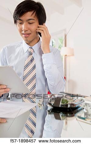 Young Asian businessman talking on his smartphone View Large Photo Image Stock Photo - Young Asian businessman talking on his smartphone. Fotosearch