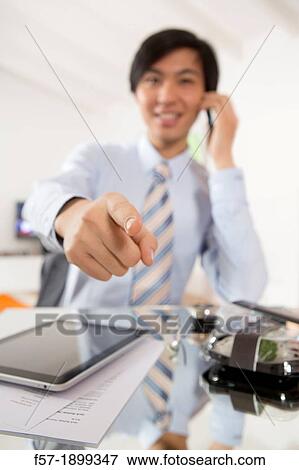 Young Asian businessman talking on his smartphone View Large Photo Image Stock Photo - Young Asian businessman talking on his smartphone. Fotosearch