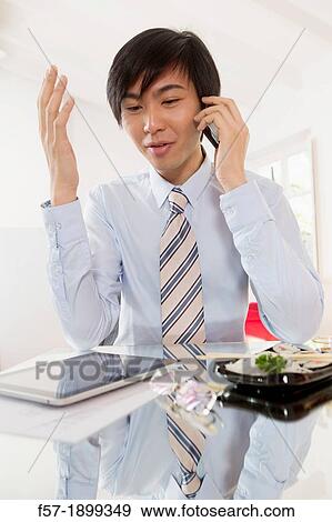 Young Asian businessman talking on his smartphone View Large Photo Image Stock Photo - Young Asian businessman talking on his smartphone. Fotosearch