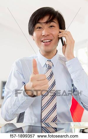 Young Asian businessman talking on his smartphone View Large Photo Image Stock Photo - Young Asian businessman talking on his smartphone. Fotosearch