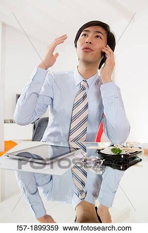 Young Asian businessman talking on his smartphone View Large Photo Image Stock Photo - Young Asian businessman talking on his smartphone. Fotosearch