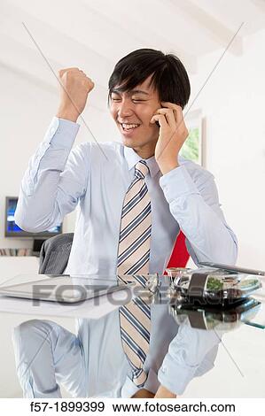 Young Asian businessman talking on his smartphone View Large Photo Image Stock Photo - Young Asian businessman talking on his smartphone. Fotosearch