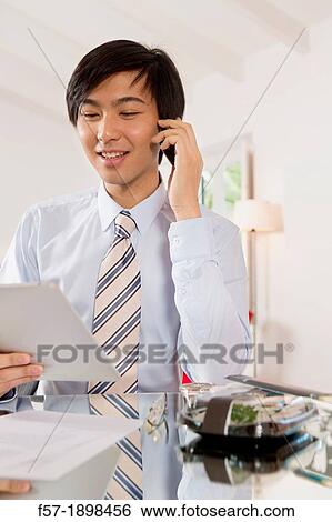 Young Asian businessman talking on his smartphone View Large Photo Image Stock Photograph - Young Asian businessman talking on his smartphone. Fotosearch