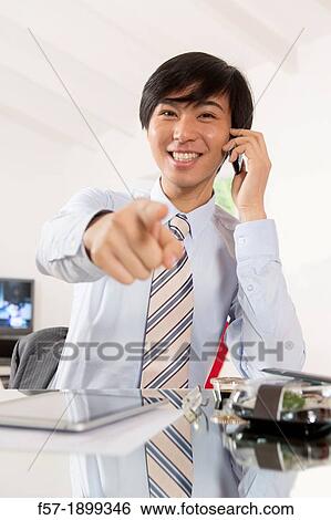 Young Asian businessman talking on his smartphone View Large Photo Image Stock Photograph - Young Asian businessman talking on his smartphone. Fotosearch