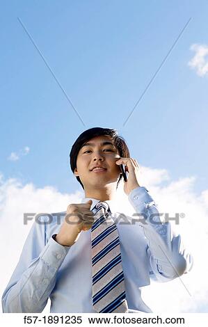 Young Asian businessman talking on his smartphone View Large Photo Image Stock Photography - Young Asian businessman talking on his smartphone. Fotosearch