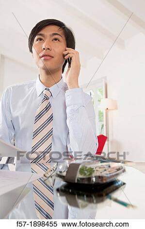 Young Asian businessman talking on his smartphone View Large Photo Image Stock Photography - Young Asian businessman talking on his smartphone. Fotosearch