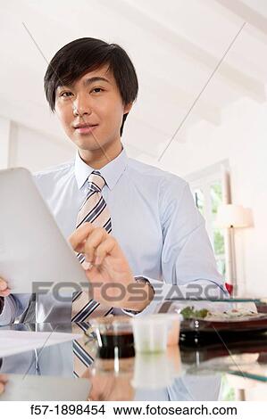 Young Asian businessman using his Tablet computer View Large Photo Image Picture - Young Asian businessman using his Tablet computer. Fotosearch