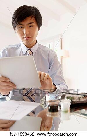 Stock Image - Young Asian businessman using his Tablet computer. Fotosearch