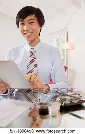 Young Asian businessman using his Tablet computer View Large Photo Image Stock Image - Young Asian businessman using his Tablet computer. Fotosearch