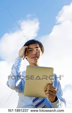Young Asian businessman using his Tablet computer View Large Photo Image Stock Photo - Young Asian businessman using his Tablet computer. Fotosearch