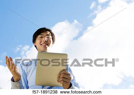 Young Asian businessman using his Tablet computer View Large Photo Image Stock Photo - Young Asian businessman using his Tablet computer. Fotosearch