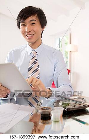 Young Asian businessman using his Tablet computer View Large Photo Image Stock Photo - Young Asian businessman using his Tablet computer. Fotosearch