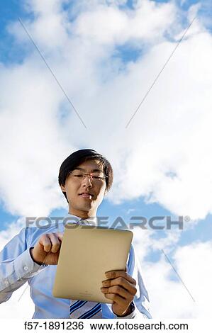 Young Asian businessman using his Tablet computer View Large Photo Image Stock Photograph - Young Asian businessman using his Tablet computer. Fotosearch