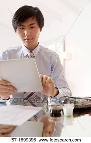 Young Asian businessman using his Tablet computer View Large Photo Image Stock Photograph - Young Asian businessman using his Tablet computer. Fotosearch