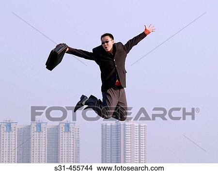 Young Asian (Chinese) businessman caught in mid-air, ground not visible, hi-rise buildings in the background View Large Photo Image Picture - Young Asian (Chinese) businessman caught in mid-air, ground not visible, hi-rise buildings in the background. Fotosearch