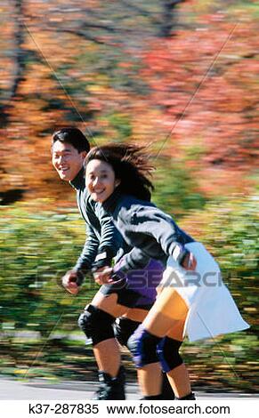 Stock Photography - Young asian couple rollerblading in park outdoors. Fotosearch