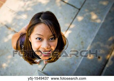 Stock Photo - Young Asian female looking up with tongue out. Fotosearch