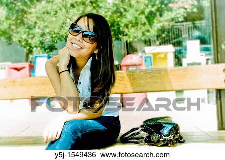 Young Asian female siting on bench View Large Photo Image Stock Photograph - Young Asian female siting on bench. Fotosearch