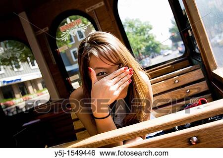 Young Asian female sitting inside a trolley, hiding her face behind hand View Large Photo Image Stock Photograph - Young Asian female sitting inside a trolley, hiding her face behind hand. Fotosearch