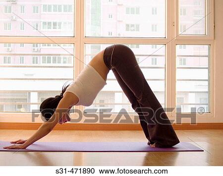 Stock Image - young asian girl practicing yoga at home. Fotosearch