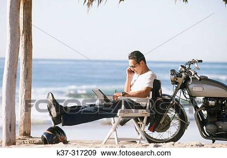 Young Asian Hawaiian man on beach on phone, with motorcycle and laptop computer View Large Photo Image Stock Photo - Young Asian Hawaiian man on beach on phone, with motorcycle and laptop computer. Fotosearch