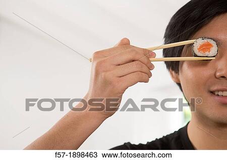 Young Asian man eating sushi View Large Photo Image Stock Image - Young Asian man eating sushi. Fotosearch