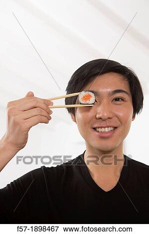 Young Asian man eating sushi View Large Photo Image Stock Photo - Young Asian man eating sushi. Fotosearch