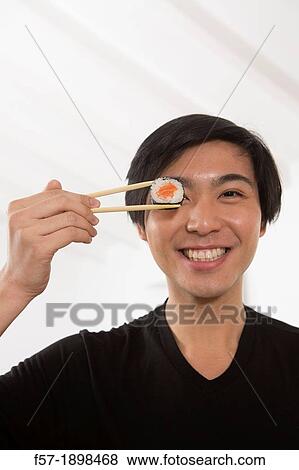 Young Asian man eating sushi View Large Photo Image Stock Photo - Young Asian man eating sushi. Fotosearch