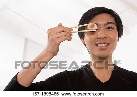 Young Asian man eating sushi View Large Photo Image Stock Photograph - Young Asian man eating sushi. Fotosearch