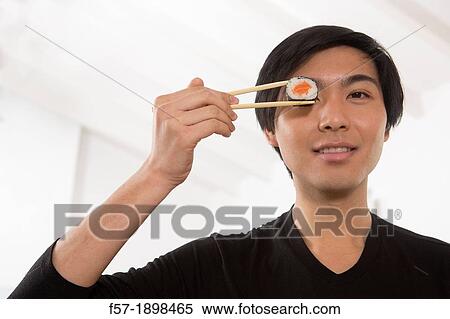 Young Asian man eating sushi View Large Photo Image Stock Photography - Young Asian man eating sushi. Fotosearch